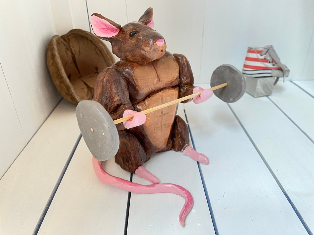 A clay sculpture of a rat, lifting dumbbells. The rat is heavily muscled.